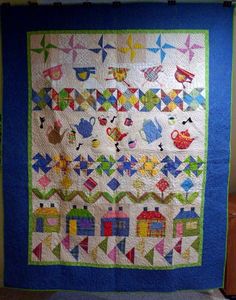 a quilted wall hanging on the side of a building with kites and boats