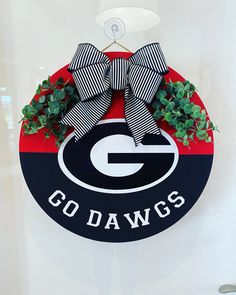 a black and red door hanger that says go dawgs with a bow on it