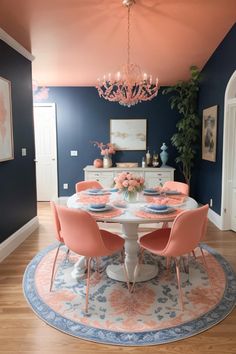 a dining room with blue walls and pink chairs around a white table in the center