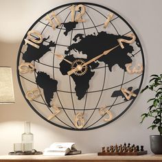 a large metal clock with gold numbers and a world map on the wall above it