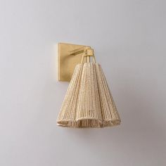 a wall light that is on the side of a white wall with a long tassel hanging from it