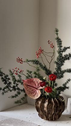 a vase filled with flowers sitting on top of a white table next to a plant