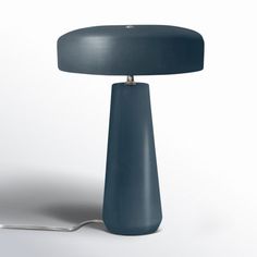 a blue table lamp sitting on top of a white floor next to a light bulb