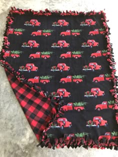 a black and red plaid blanket with an old truck pattern on the bottom, sitting on top of a floor