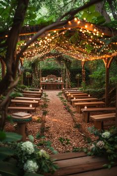 an outdoor wedding venue with wooden benches and string lights hanging from the ceiling, surrounded by greenery