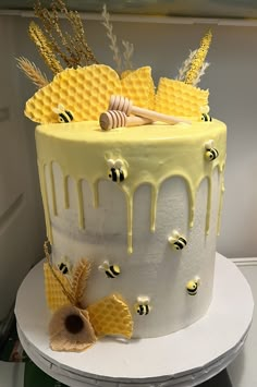 a yellow and white cake with honeycombs on it's sides, topped with bees