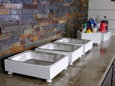 three white trays sitting on top of a counter in front of a brick wall