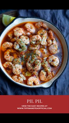 a bowl of shrimp and tomato soup with a lime slice on the side