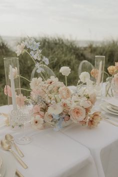 a table set with flowers and candles for an elegant wedding reception at the beach side