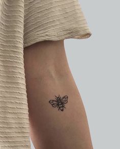 a woman's arm with a small black butterfly tattoo on the left side of her body