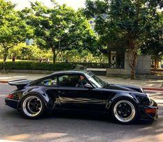 a black sports car parked on the side of the road in front of some trees