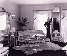 a black and white photo of a woman standing in front of a couch with mirrors on it