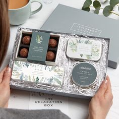 a woman holding a box of chocolates next to a cup and saucer on a table