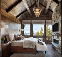 a bedroom with a stone fireplace and large windows overlooking the mountain range is shown in this image