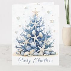 a christmas card with seashells and starfish on it, next to a potted plant