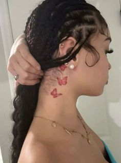 a woman is getting her hair done with red butterflies on the back of her neck