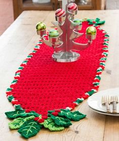 a crocheted christmas table runner on a wooden table with silverware and plates