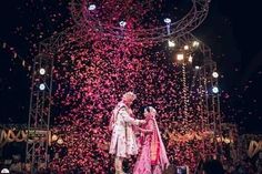 two people standing in front of a stage with confetti falling from the ceiling