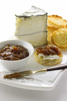 a white plate topped with slices of cake next to a bowl of jelly and bread