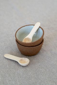 two bowls with spoons sitting on the ground