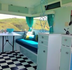 a kitchen area with a table, sink and window in the back side of a camper