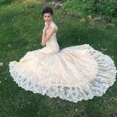 a woman is sitting on the grass wearing a dress with white laces and beads