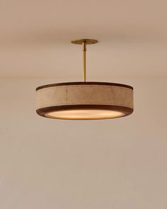 a round light fixture hanging from the ceiling in a room with beige walls and flooring