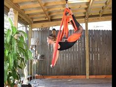 a woman in an orange shirt is doing aerial acrobatics on a hammock