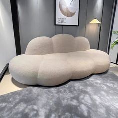 a large white couch sitting on top of a carpet covered floor next to a lamp