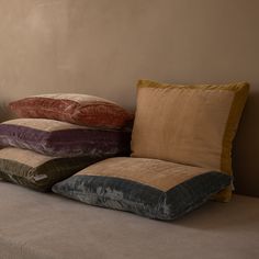 four pillows stacked on top of each other in front of a wall with a window