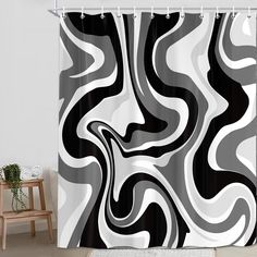 a black and white shower curtain with an abstract swirl design on the bottom, in front of a chair