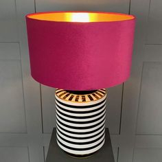 a pink lamp sitting on top of a table next to a black and white vase