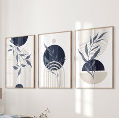 three framed art pieces hang on the wall above a bed in a room with white walls