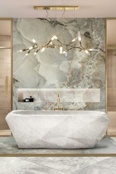 an elegant bathroom with marble walls and flooring, gold chandelier above the bathtub