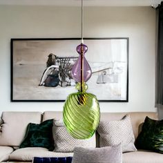 a living room filled with furniture and a painting hanging from the ceiling above it's coffee table