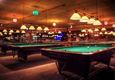 a pool table with several lights hanging from the ceiling