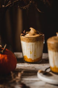 two desserts sitting on top of a table next to each other with pumpkins in the background