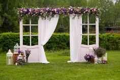 an outdoor wedding ceremony setup with flowers on the windowsills and white drapes