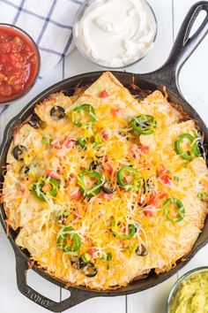 an enchilada in a cast iron skillet with salsa and sour cream