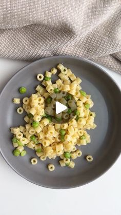 a plate filled with macaroni and peas on top of a table