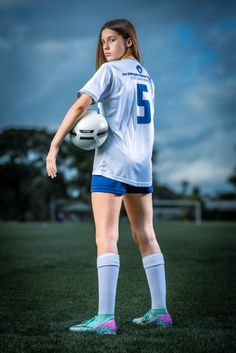 a female soccer player is posing for a photo on the field with a ball in her hand