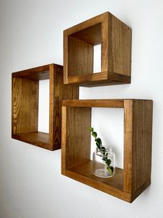 two wooden shelves with vases and flowers in them hanging on the wall next to each other