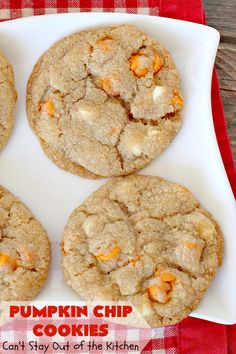 four pumpkin chip cookies on a plate with a red and white checkered tablecloth