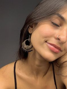 a close up of a person wearing some kind of earring on her head and looking at the camera