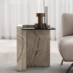 a marble side table with candles on it in front of a chair and curtained window