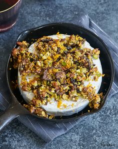 a pan filled with food sitting on top of a table next to a glass of wine