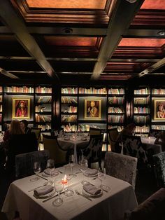 a dining room with tables and chairs in front of bookshelves filled with books