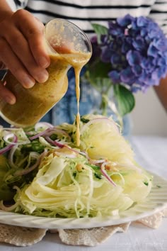 someone pouring dressing onto a plate of salad