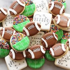 decorated cookies with footballs and sprinkles on top of a marble table