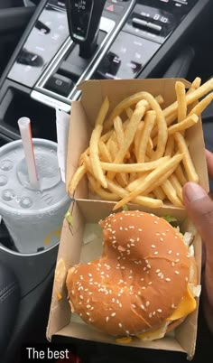 a hand holding a box with a hamburger and french fries in it